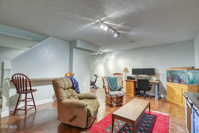 living area with rail lighting, a textured ceiling, baseboards, and wood finished floors