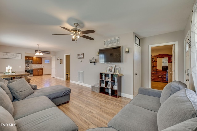 living area with a ceiling fan, light wood-style flooring, visible vents, and baseboards