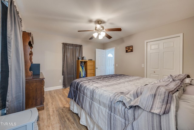 bedroom featuring a ceiling fan, a closet, light wood-style flooring, and baseboards