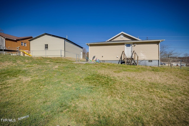 back of house featuring entry steps, crawl space, a lawn, and fence