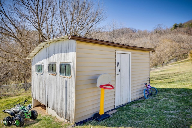 view of outbuilding featuring fence and an outbuilding