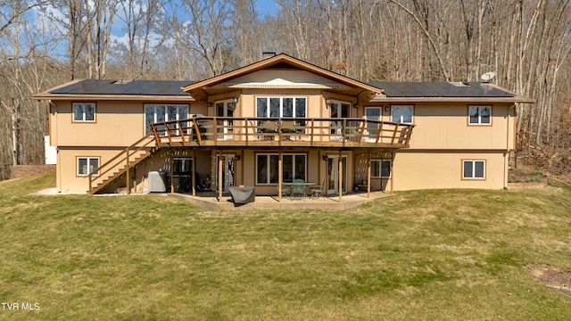 back of house featuring a yard, solar panels, a patio area, a wooden deck, and stairs