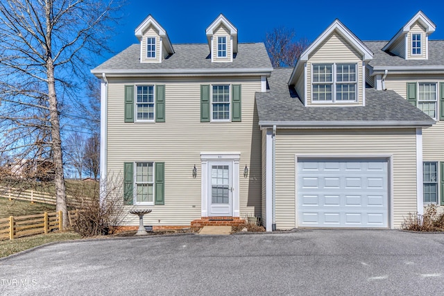 view of front of house featuring aphalt driveway, fence, a shingled roof, and an attached garage