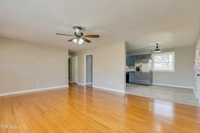 unfurnished living room featuring light wood-style floors, baseboards, and a ceiling fan