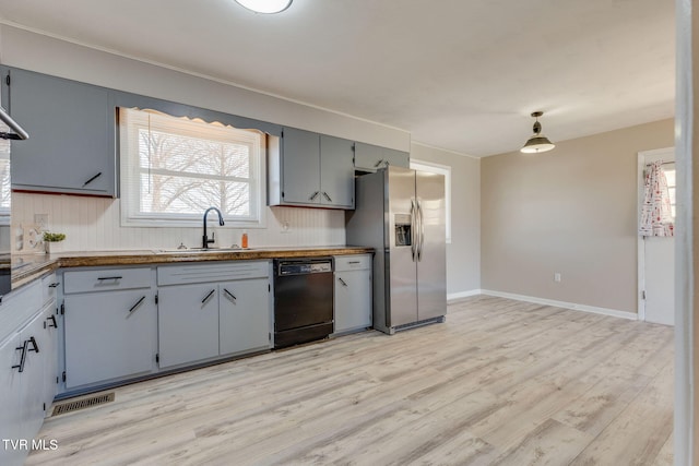 kitchen with a sink, light wood-type flooring, stainless steel fridge, and dishwasher