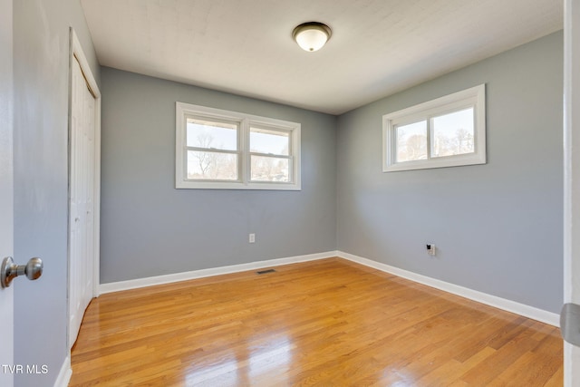 unfurnished bedroom featuring a closet, visible vents, baseboards, and light wood finished floors