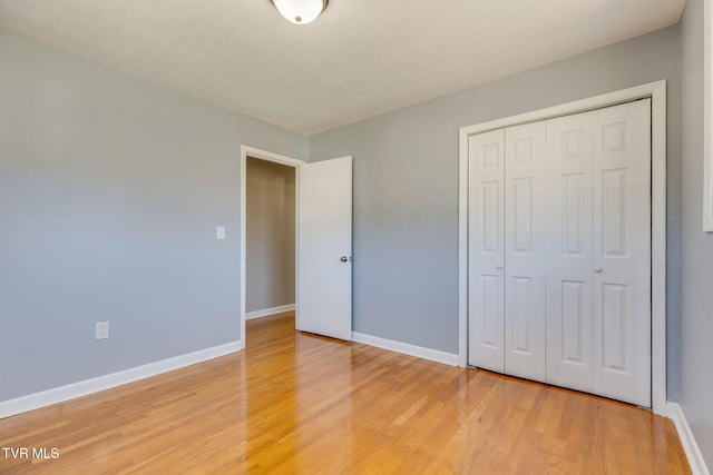 unfurnished bedroom with light wood-style floors, baseboards, and a closet