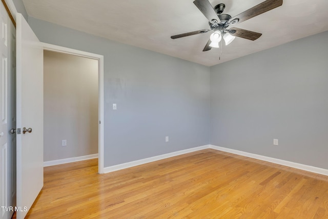 empty room with light wood finished floors, baseboards, and a ceiling fan