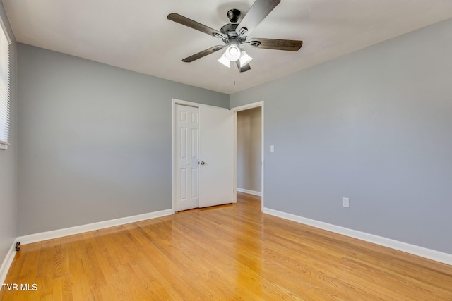 empty room with light wood finished floors, a ceiling fan, and baseboards