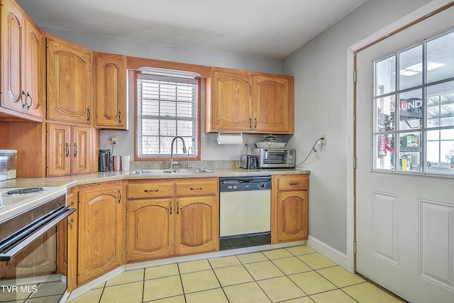 kitchen featuring light tile patterned floors, light countertops, white dishwasher, a sink, and range with electric cooktop