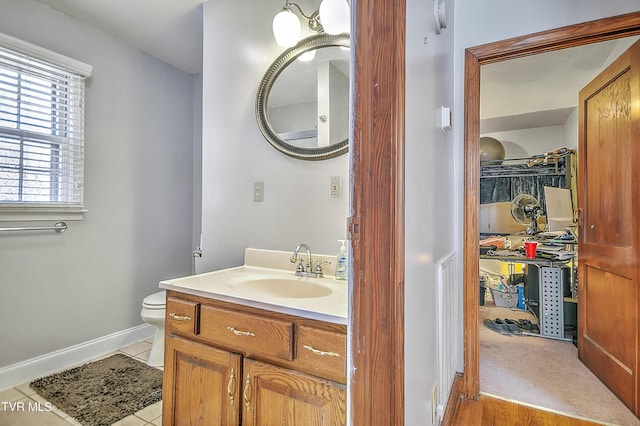 bathroom with tile patterned flooring, baseboards, vanity, and toilet