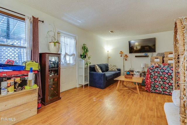 living room featuring a textured ceiling, visible vents, and wood finished floors