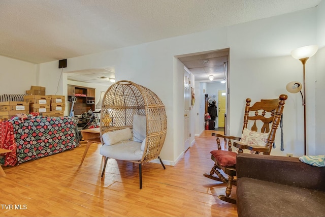 interior space with a paneled ceiling, a textured ceiling, baseboards, and wood finished floors