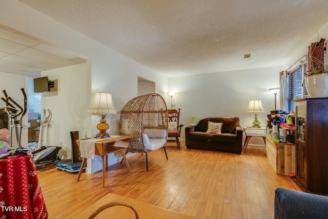 living area with a textured ceiling, light wood finished floors, and visible vents