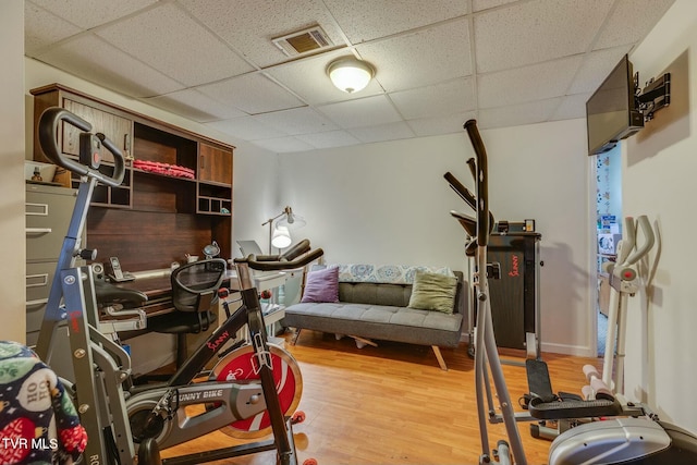 exercise area featuring visible vents, a drop ceiling, and wood finished floors