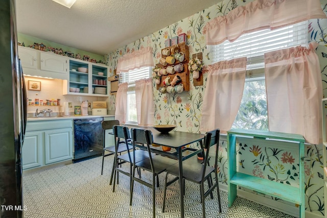 dining area featuring a textured ceiling and wallpapered walls