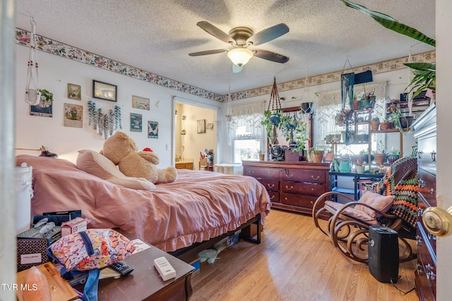 bedroom with ensuite bath, ceiling fan, a textured ceiling, and wood finished floors