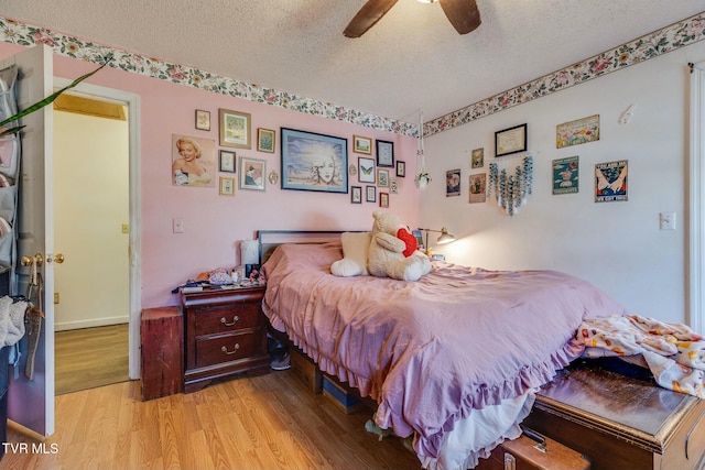 bedroom featuring a textured ceiling, light wood finished floors, and a ceiling fan