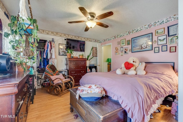 bedroom featuring a textured ceiling, a spacious closet, a closet, and light wood-style flooring