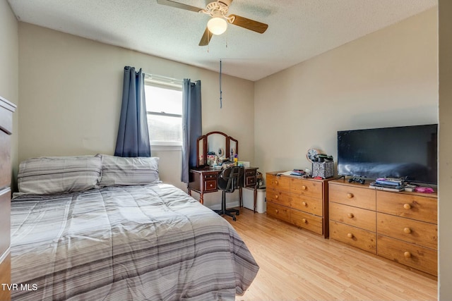 bedroom featuring light wood finished floors, a ceiling fan, and a textured ceiling