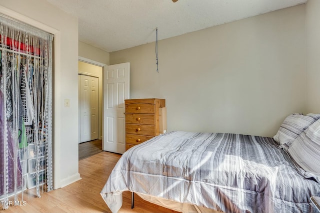 bedroom featuring a textured ceiling, baseboards, and wood finished floors