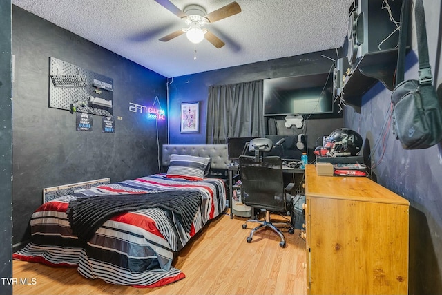 bedroom with ceiling fan, a textured ceiling, and wood finished floors