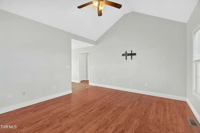 spare room with visible vents, a ceiling fan, wood finished floors, high vaulted ceiling, and baseboards