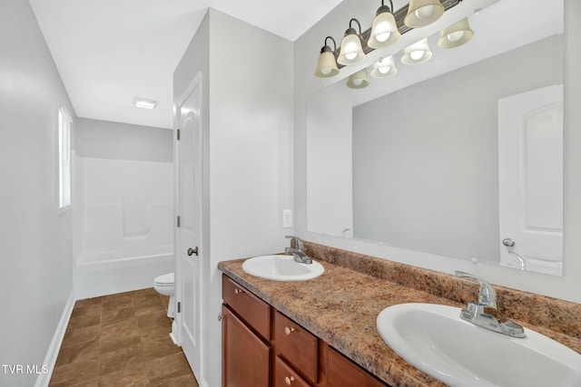 full bathroom featuring double vanity, baseboards, toilet, and a sink