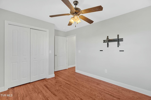 unfurnished bedroom with a closet, wood finished floors, a ceiling fan, and baseboards