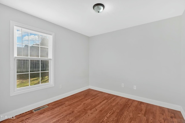 unfurnished room with wood finished floors, visible vents, and baseboards