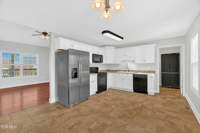 kitchen featuring light countertops, visible vents, white cabinets, a sink, and black appliances