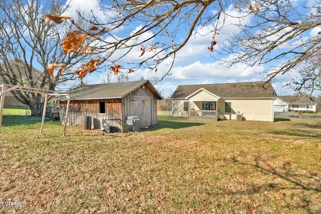 back of house featuring an outbuilding, a yard, and a shed