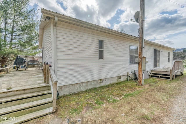 view of side of home featuring crawl space, a wooden deck, and fence