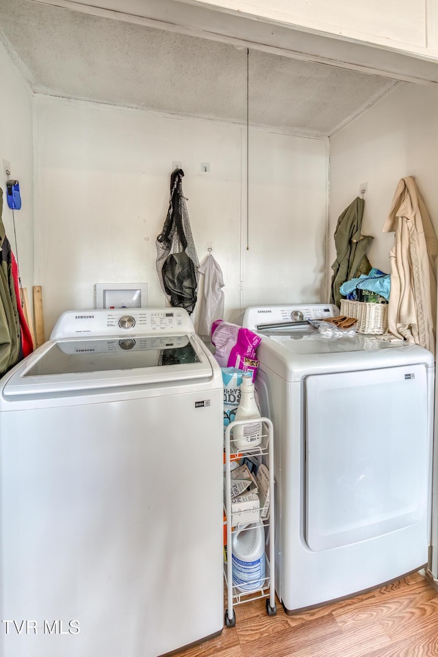 clothes washing area with light wood-style floors, laundry area, and washing machine and clothes dryer