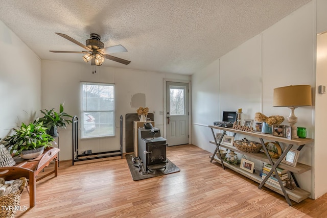 sitting room with light wood-type flooring, plenty of natural light, ceiling fan, and a textured ceiling