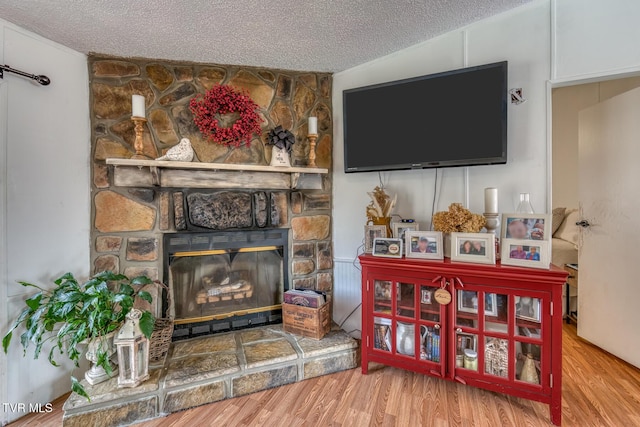 room details featuring a fireplace, a textured ceiling, and wood finished floors