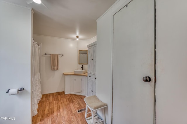 bathroom featuring a shower with shower curtain, ornamental molding, wood finished floors, and vanity