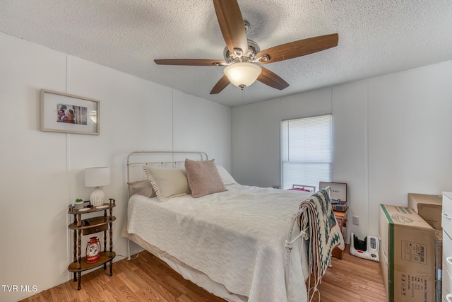 bedroom featuring ceiling fan, a textured ceiling, and wood finished floors