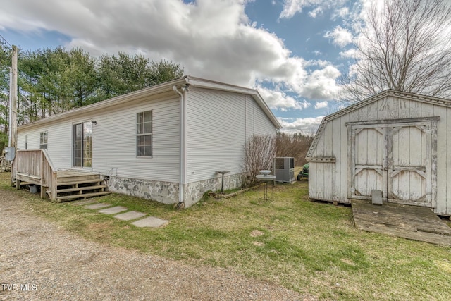 exterior space featuring a shed, a deck, a lawn, and an outbuilding