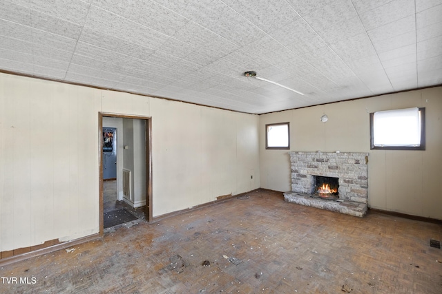 unfurnished living room with visible vents, plenty of natural light, and a stone fireplace