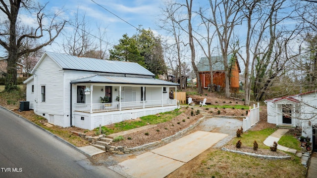 view of front of home with cooling unit, covered porch, driveway, and metal roof