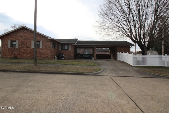 ranch-style house featuring a carport, brick siding, driveway, and fence