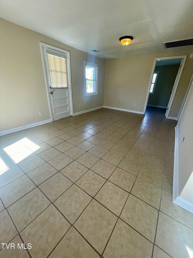 unfurnished room with light tile patterned flooring, visible vents, and baseboards