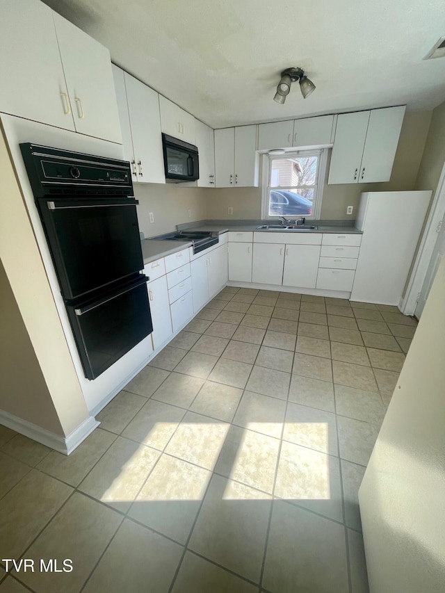 kitchen with visible vents, black appliances, a sink, white cabinets, and light tile patterned floors