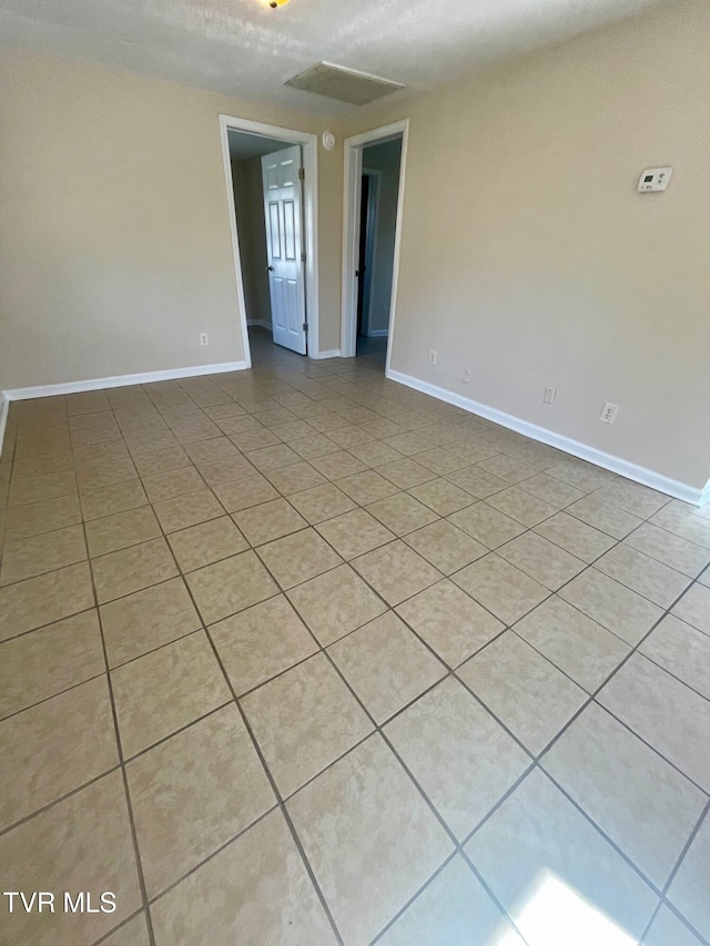 spare room featuring light tile patterned flooring and baseboards