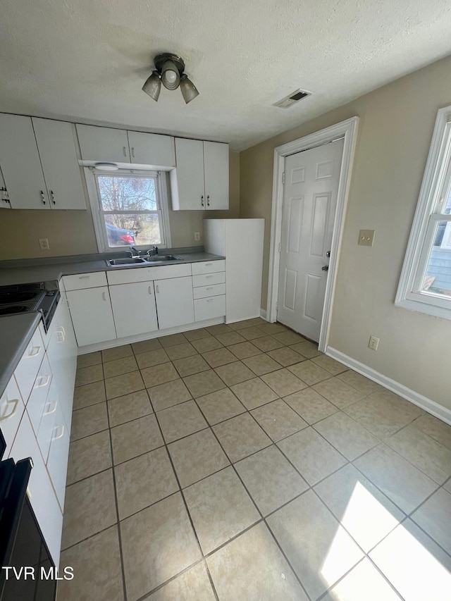 kitchen featuring white cabinetry, light tile patterned floors, visible vents, and a textured ceiling