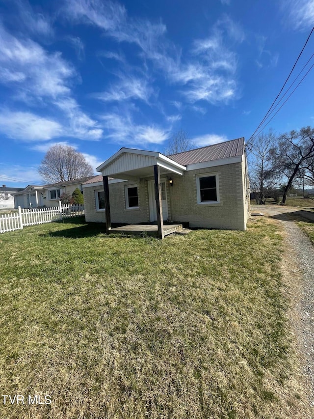 back of house featuring a yard, fence, and metal roof