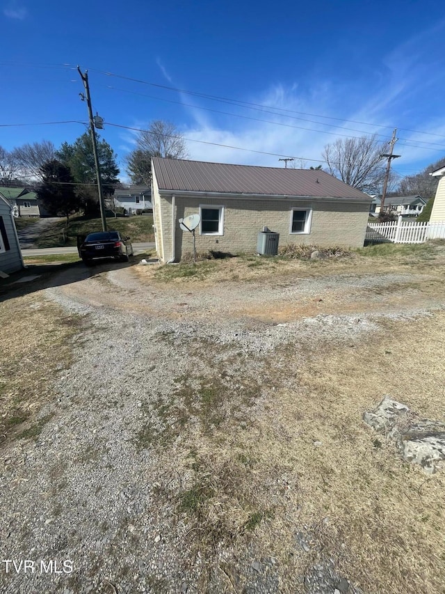 exterior space with metal roof, dirt driveway, and fence