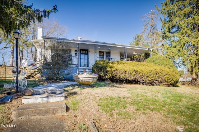 view of front facade with covered porch, a front lawn, and a chimney