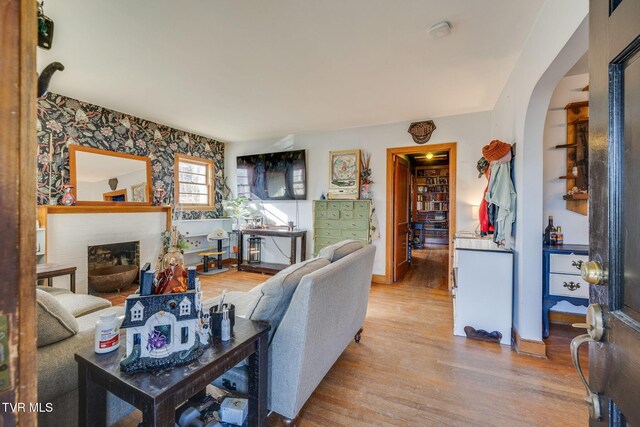 living room featuring a brick fireplace and wood finished floors